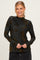 woman wearing a black long sleeve top with floral print and a mock neck, smiling at the camera