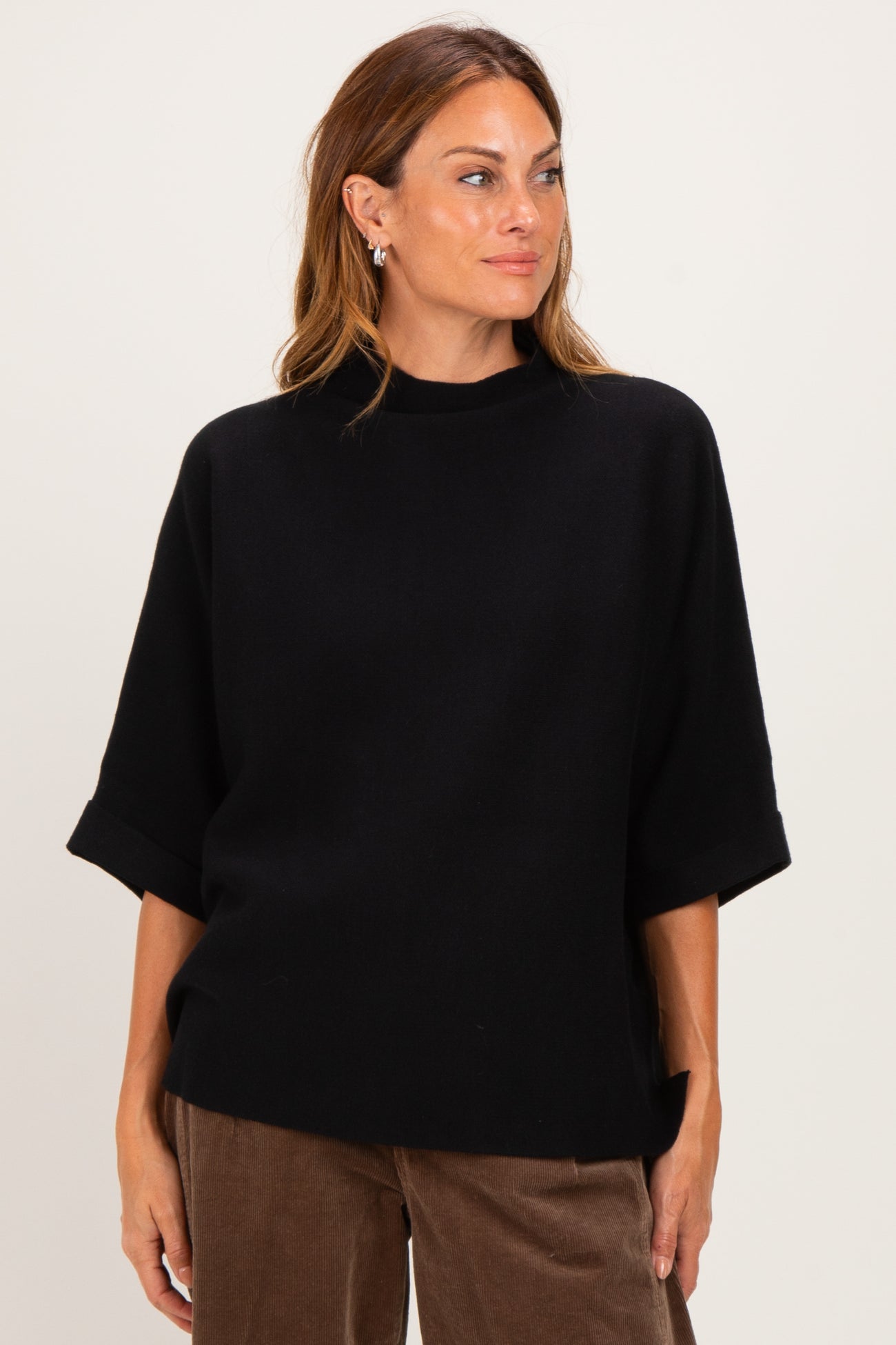 woman wearing a black oversized sweater with a high neckline and wide sleeves