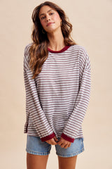 woman wearing a striped long sleeve top with a burgundy trim and denim shorts