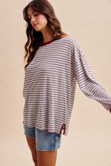 woman wearing a striped oversized long sleeve top in beige and burgundy with denim shorts