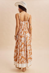 woman wearing a back view of a brown floral maxi dress with adjustable straps and a smocked bodice