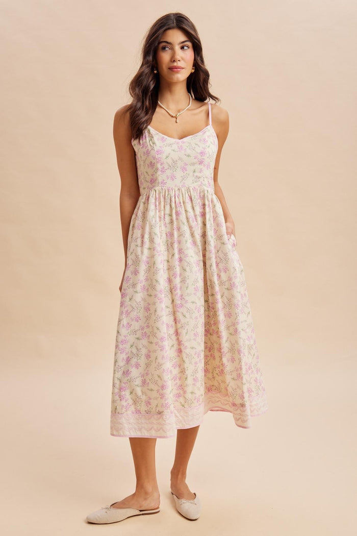 woman wearing a pastel pink floral midi sundress with thin straps and pockets