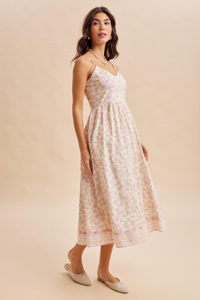 woman wearing a floral print midi dress with thin straps and a flowy skirt