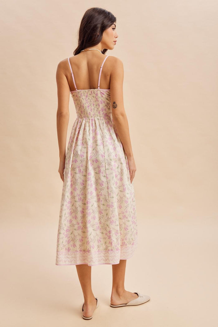 woman wearing a floral print midi dress with thin straps and a smocked back, viewed from behind
