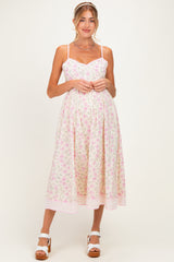 woman wearing a pastel floral print maternity dress with a sweetheart neckline and adjustable straps