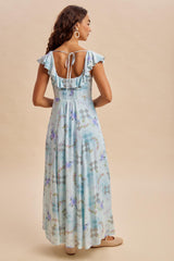woman wearing a light blue floral maxi dress with ruffled sleeves and an open back detail, viewed from the back