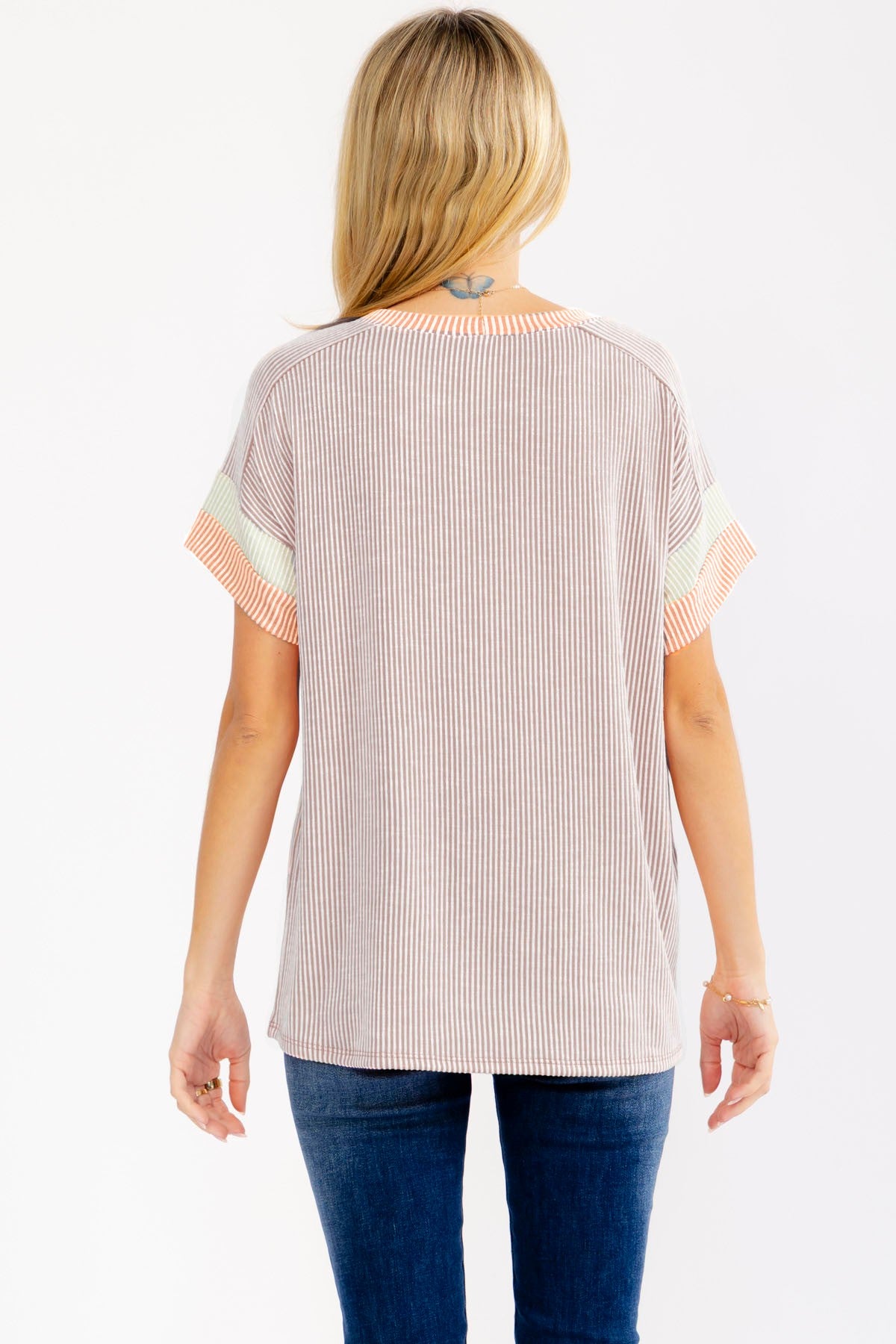 woman wearing a striped short sleeve top with orange and green color block details, viewed from the back