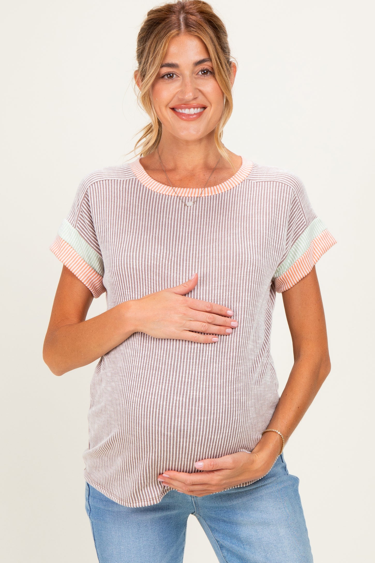 woman wearing a striped maternity top with short sleeves and holding her baby bump