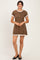 woman wearing a brown polka dot dress with short sleeves and ruffled hem