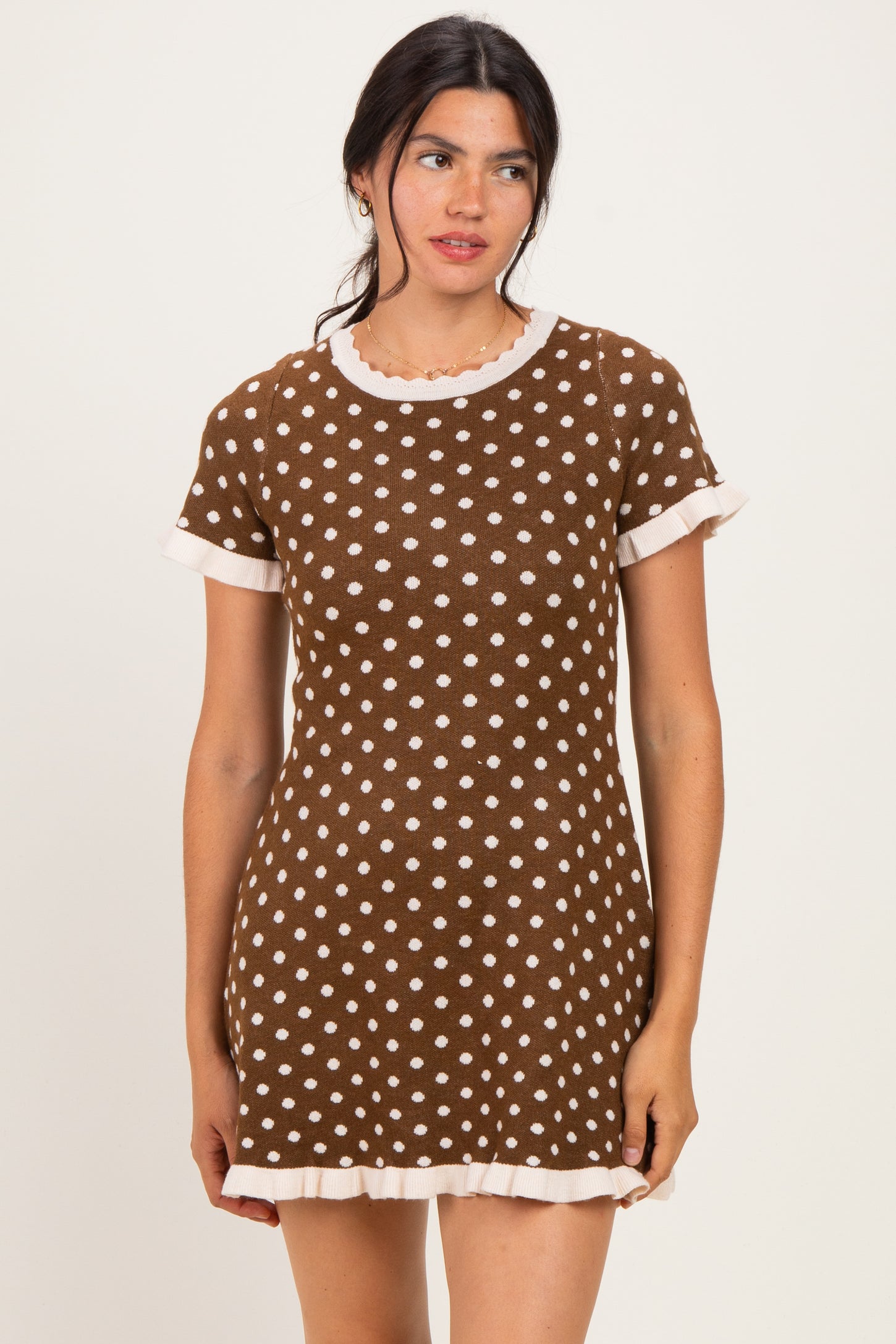 woman wearing a brown polka dot mini dress with white trim and short sleeves