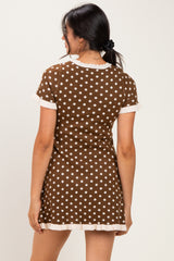 woman wearing a brown polka dot short sleeve dress with white trim visible from the back