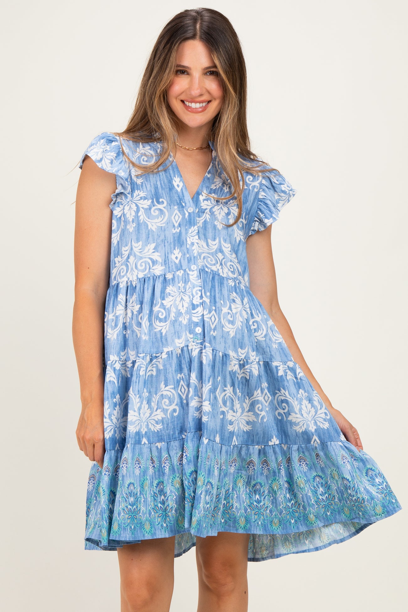woman wearing a blue floral print maternity dress with ruffle sleeves and a tiered skirt