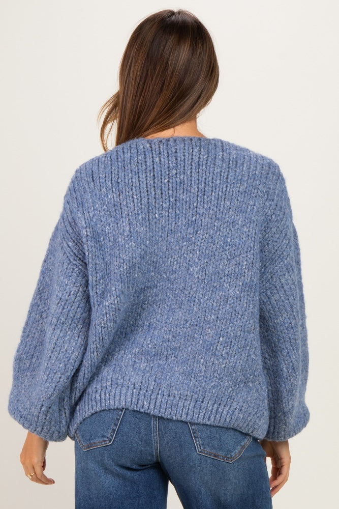 woman wearing a cozy blue knitted maternity sweater with balloon sleeves and a relaxed fit, seen from the back