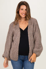 woman wearing a brown chunky knit cardigan over a black tank top, showcasing her baby bump in maternity wear