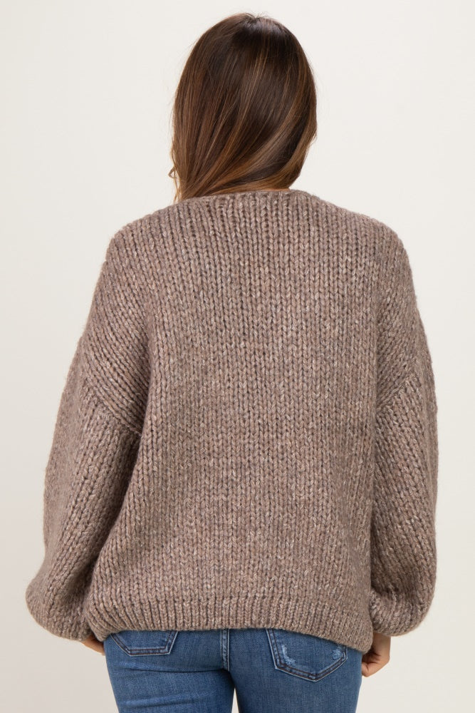 woman wearing a cozy brown chunky knit maternity sweater with a relaxed fit and balloon sleeves