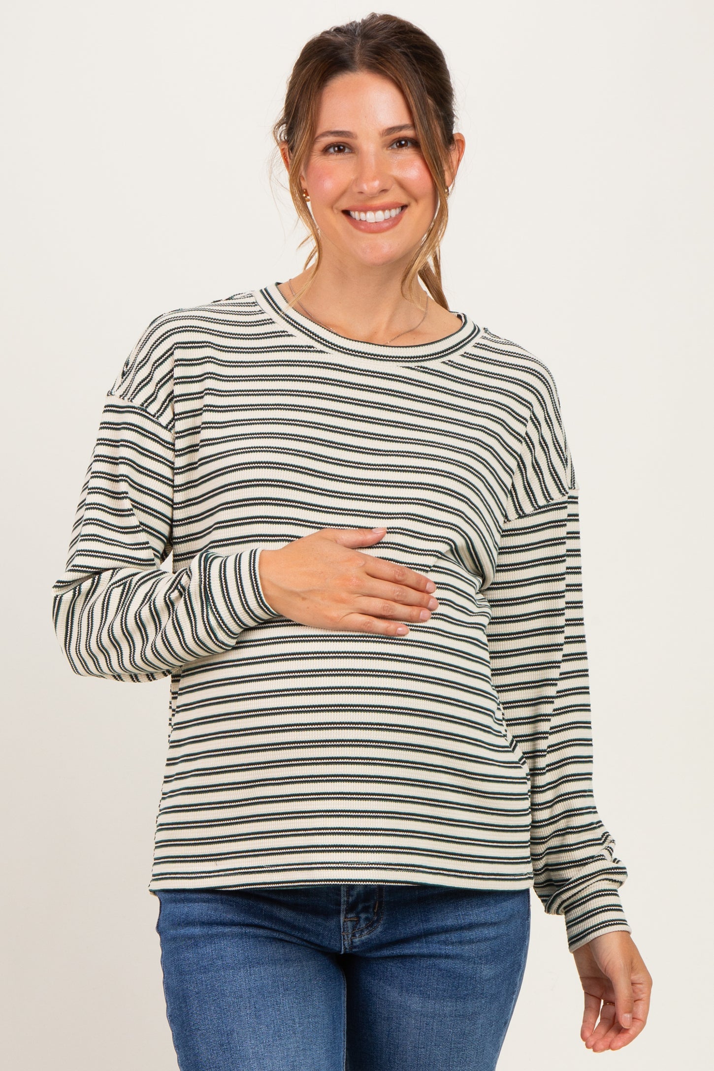 woman wearing a striped maternity top with long sleeves and holding her baby bump
