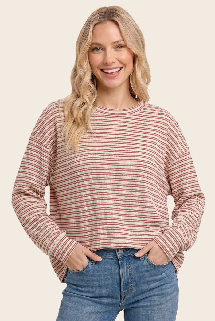woman wearing a striped long sleeve oversized top in pastel colors with a relaxed fit and a round neckline