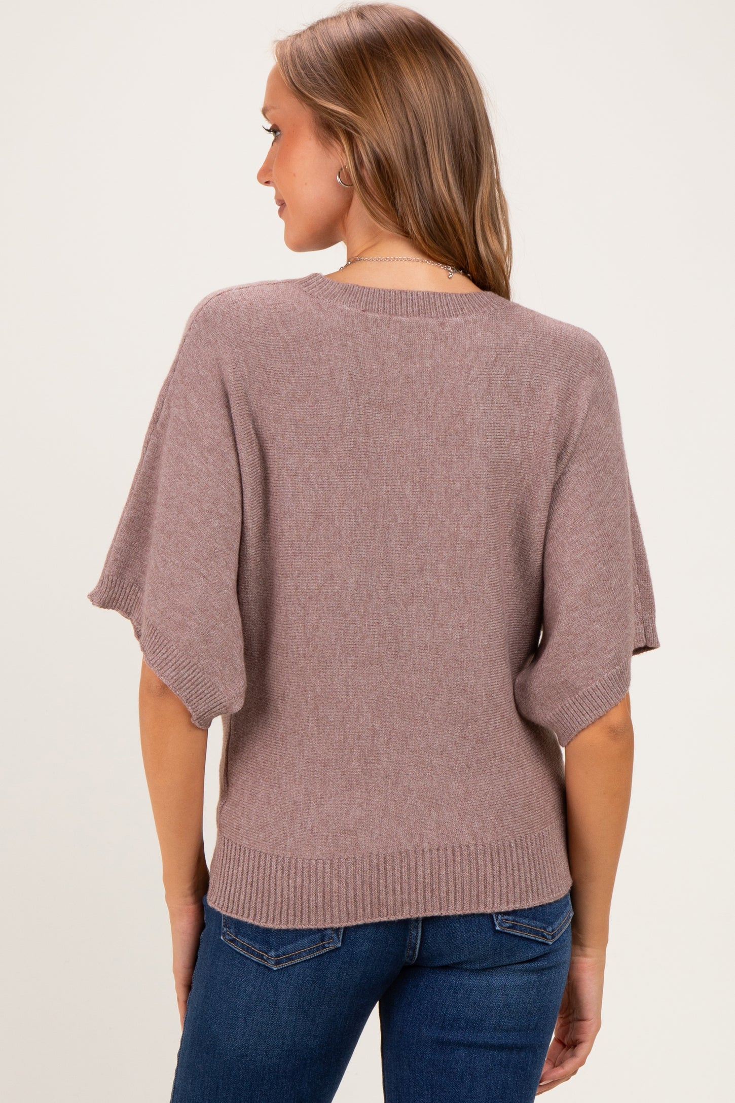 woman wearing a mauve oversized maternity sweater with short sleeves, viewed from the back