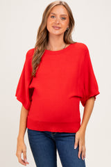 woman wearing a bright red short sleeve maternity sweater and showing her baby bump