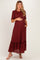 woman wearing a burgundy floral maternity dress with a ruffled hem and short sleeves, holding her baby bump