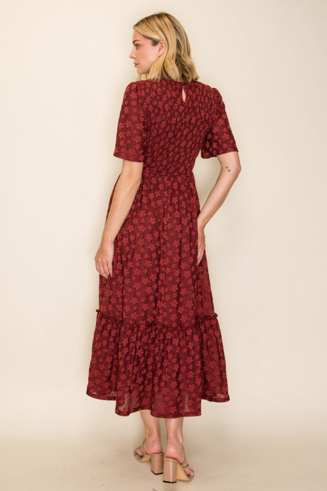 woman wearing a burgundy floral midi dress with short sleeves and a ruffled hem, shown from the back