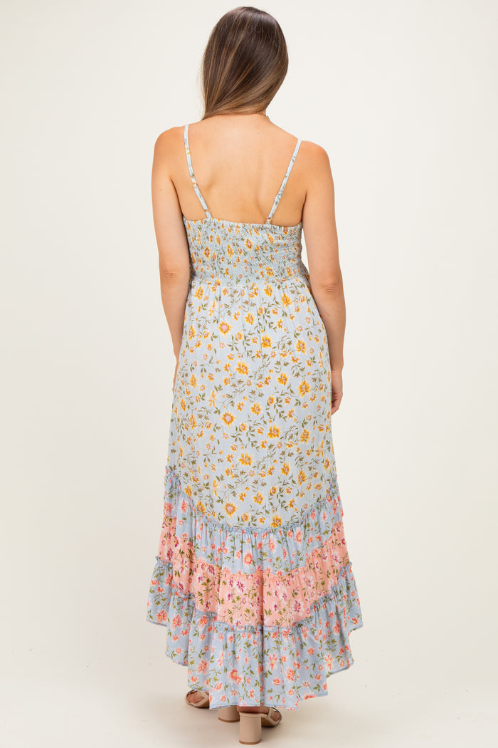 woman wearing a light blue maternity maxi dress with floral prints and a ruffled hem, showing her back