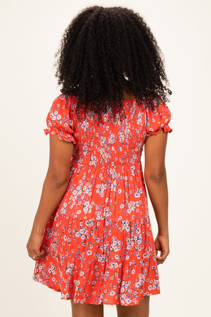 woman wearing a red floral print short dress with a smocked back and puff sleeves