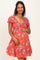 woman wearing a red floral maternity dress with short puff sleeves and a fitted bodice, holding her baby bump