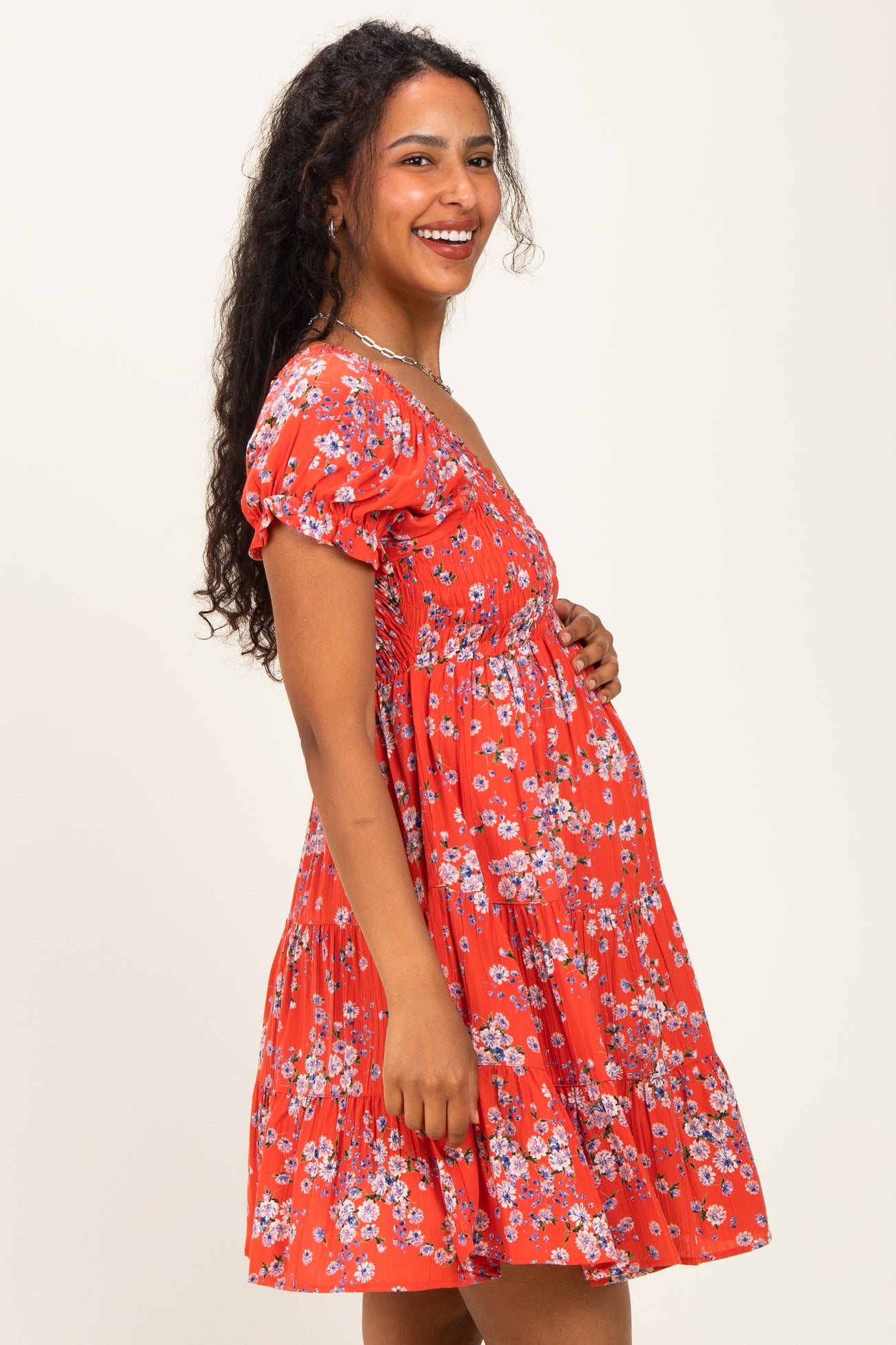 woman wearing a red floral maternity dress with short sleeves and a baby bump visible