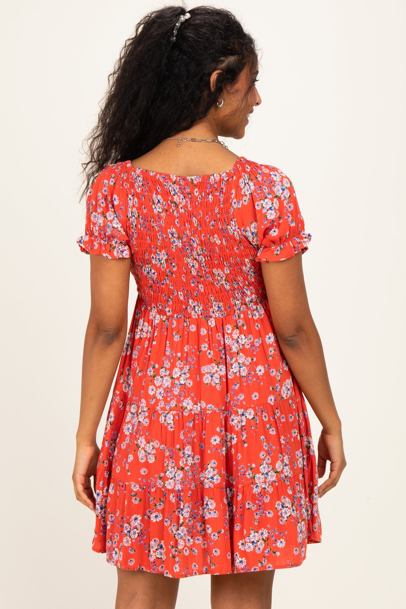 woman wearing a red floral maternity dress with short sleeves and a smocked back detail