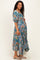 woman wearing a floral teal maternity dress with puff sleeves and a gathered waist, showing her baby bump
