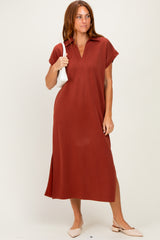 woman wearing a rust-colored short sleeve midi dress with a collar and side slits, holding a white handbag