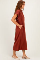 woman wearing a rust-colored short sleeve midi dress with a collar and side pockets