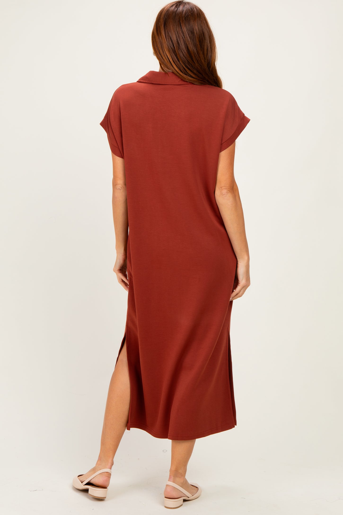 woman wearing a rust-colored midi dress with short sleeves and side slits, viewed from the back