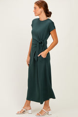 woman wearing a dark green short sleeve maxi dress with a tie waist and white block heel sandals