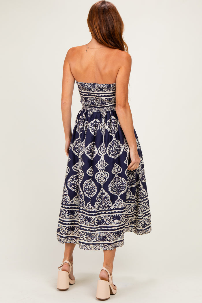 woman wearing a navy blue strapless maxi dress with a white floral pattern and a fitted bodice