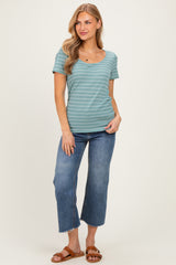 woman wearing a teal striped short sleeve t-shirt and high-waisted wide-leg jeans, standing with one hand on her hip