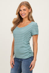 woman wearing a teal striped short sleeve top with gathered sides and a scoop neckline, paired with blue jeans