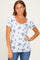 woman wearing a white short sleeve scoop neck top with blue floral print