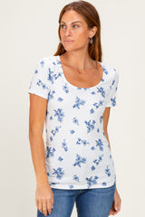 woman wearing a white short sleeve top with blue floral print and a scoop neck, paired with denim jeans