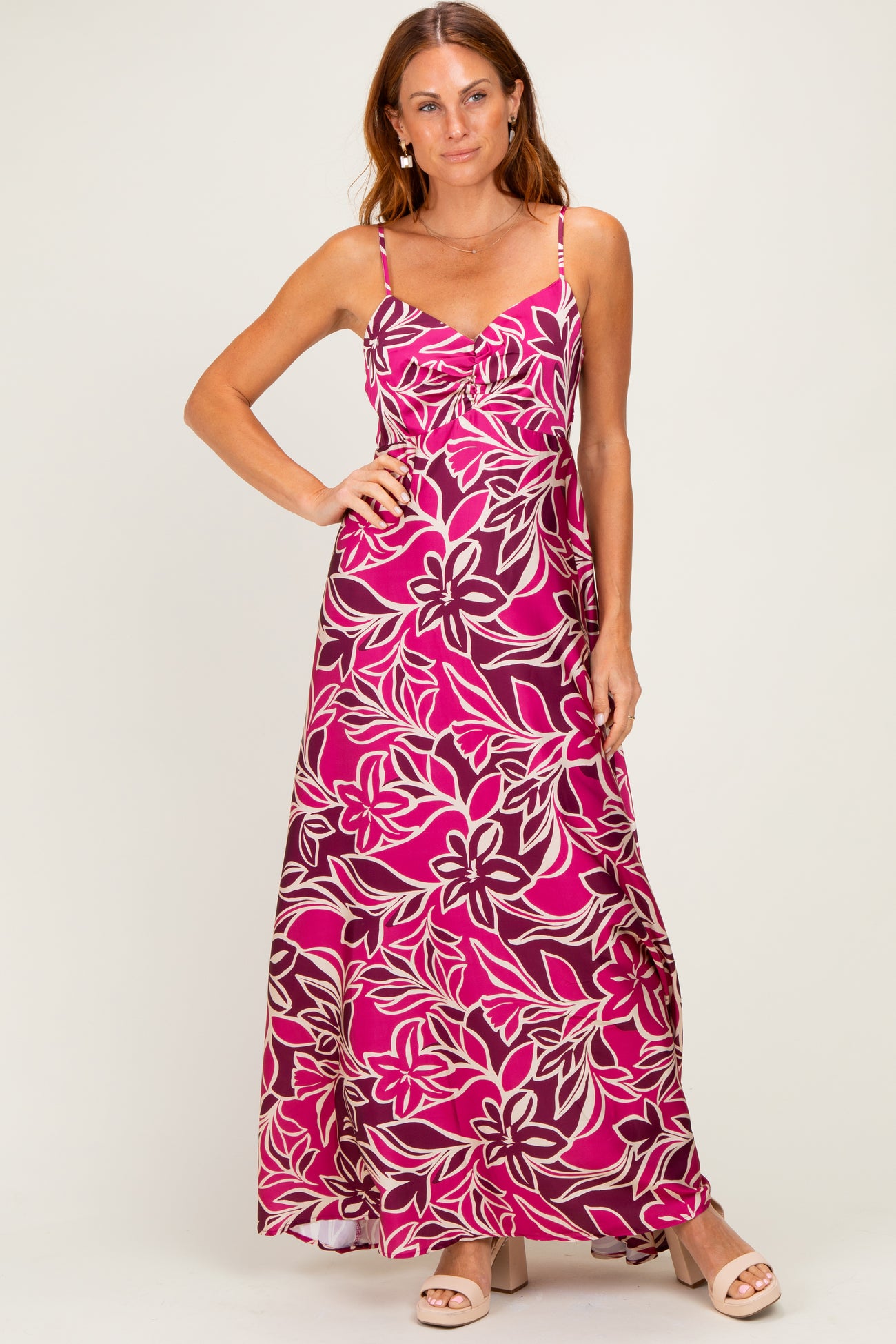 woman wearing a pink floral maxi dress with adjustable spaghetti straps and a flowy silhouette