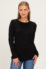woman wearing a black long sleeve top with a round neckline and jeans