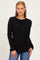 woman wearing a black long sleeve top with a round neckline and jeans