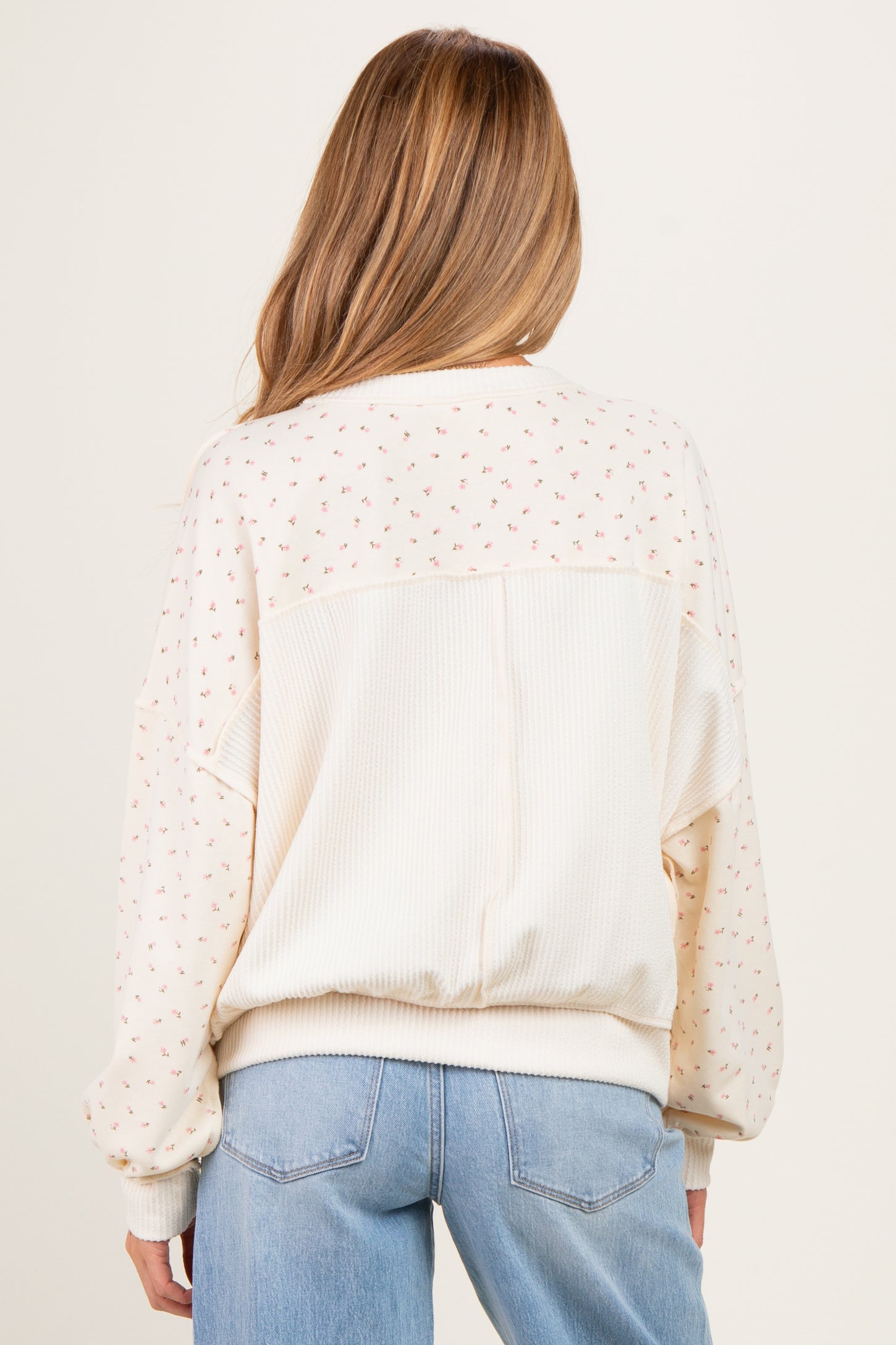 woman wearing a cream-colored floral-print maternity sweatshirt with a relaxed fit and long sleeves, seen from the back