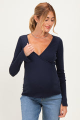 woman wearing a navy blue long sleeve wrap maternity top and showing her baby bump