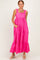 woman wearing a pink maxi dress with ruffle straps and a tiered hem, standing with hands in pockets