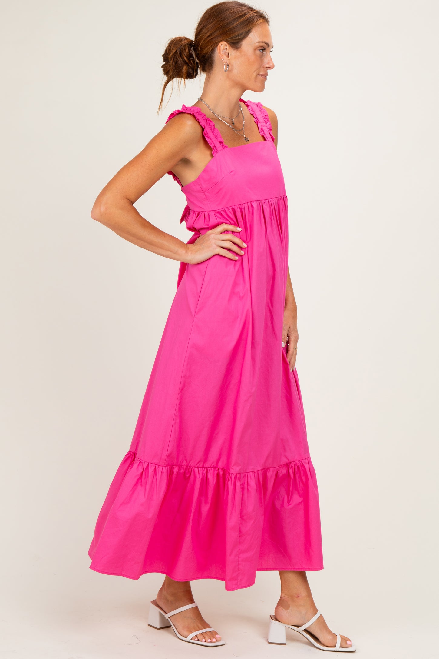 woman wearing a bright pink sleeveless maxi dress with ruffle straps and a tiered hemline