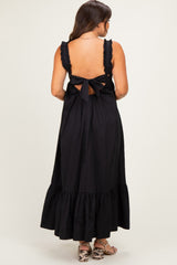 woman wearing a black maternity dress with ruffled straps and a tie-back detail, long skirt with a flared hem