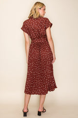 woman wearing a maroon polka dot midi dress with short sleeves and a cinched waist, shown from the back