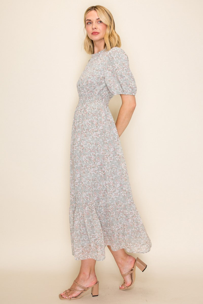 woman wearing a light blue floral midi dress with puff sleeves and a tiered skirt, paired with strappy heels